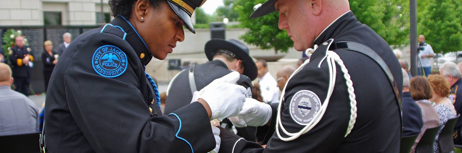 Two police honor guard officers adjusting a uniform before a ceremony